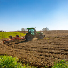 Fototapeta na wymiar Tracteur et fermier au travail dans un champ durant les labours.