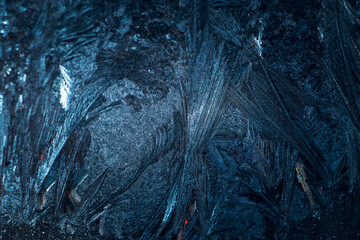 Frosty patterns on glass. Christmas background. Blue ice on winter window. Abstract texture