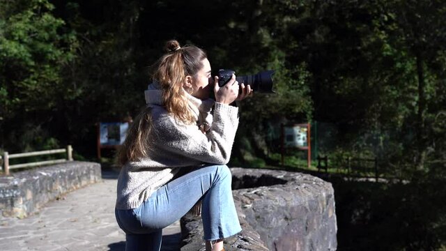 Young woman taking a picture outdoors with a professional dslr camera.