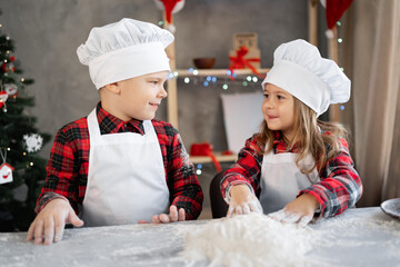 Happy brother sister make dough for Christmas cookies, children in the kitchen are preparing...