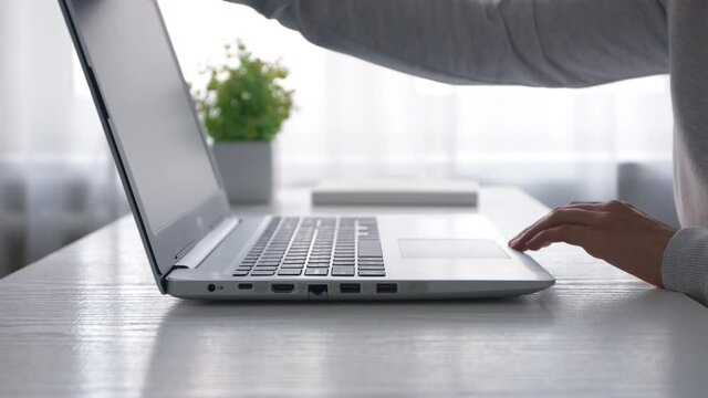 Woman's hands open a laptop and work on the keyboard. Slow motion.