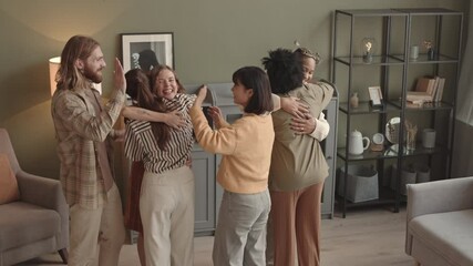 High angle of six young multiethnic female and male friends hugging each other when meeting after long time in apartment, smiling and talking - Powered by Adobe