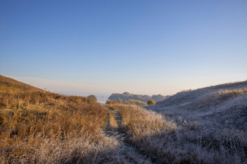 Autumn landscape in the early morning. Fog-covered expanses through which the first rays of the rising sun pass. Trees and hills in the fog. Dawn on a cold autumn morning.