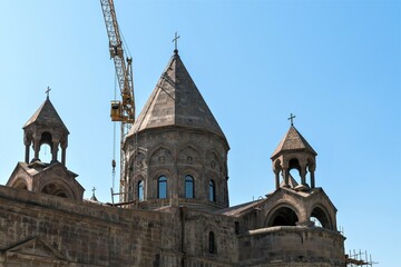 Fototapeta na wymiar Armenia, Echmiadzin, September 2021. Ancient Christian cathedral and modern construction crane.