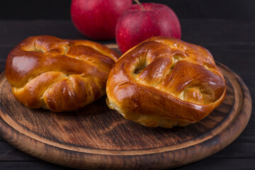 Naklejka na ściany i meble Baked yeast buns with apple on wooden board on dark background