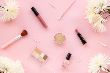 Foundation in a jar, lipstick, nail polish, eyeshadows, make up brush and lip gloss on pink...