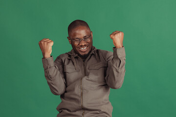 Winning success happy man celebrating being a winner. Dynamic image of male model isolated on dark green studio background