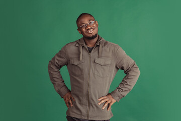 Portrait of young happy african man wearing casual clothes isolated on dark green studio background. Emotions, facial expression concept.