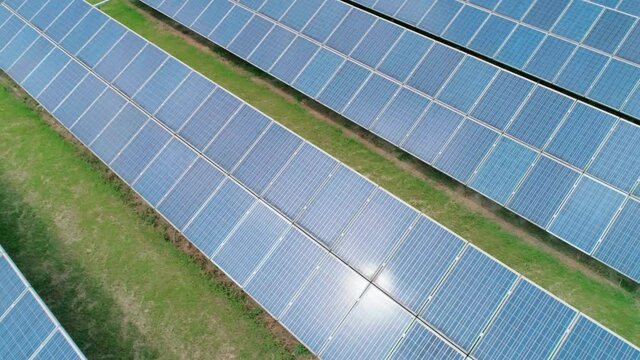 Aerial view of Solar Panels Farm solar cell with sun reflections. Renewable green alternative energy concept. Camera moves left