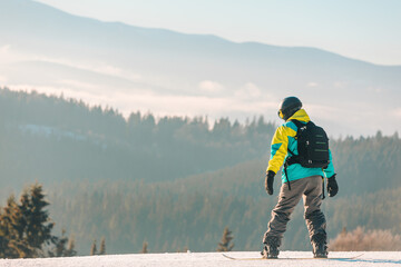 man snowboarding down by hill mountains on background