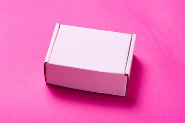 Simple pink cardboard box on color background, opened, empty inside