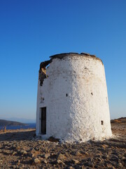 Ancient dilapidated mills on a mountain cape, against the background of the blue sea and the summer...