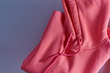 Close-up of hoodie pink trend color folded on violent bacground with hood on top with copy space.
