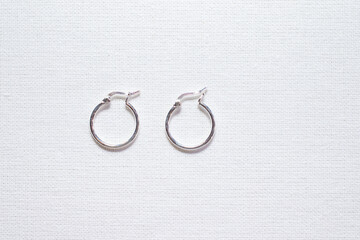 Hoop silver earrings on white cloth background