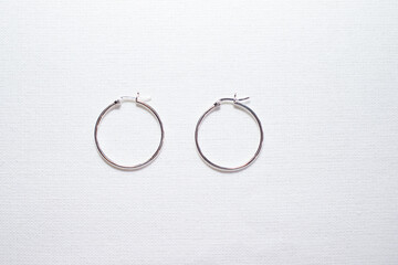 Hoop silver earrings on white cloth background