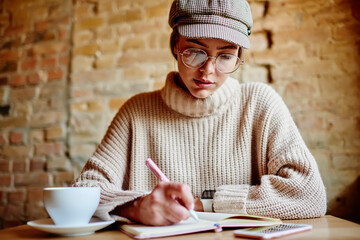 Focused woman student taking notes in notepad