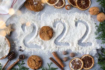  Christmas background with spices, cookies and painted number 2022 on flour. Happy New Year