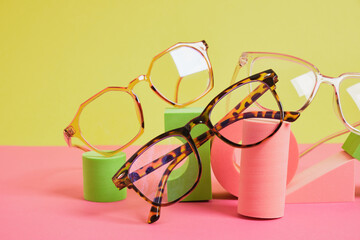 trendy eye glasses on geometric pink podiums, colorful background, copy space