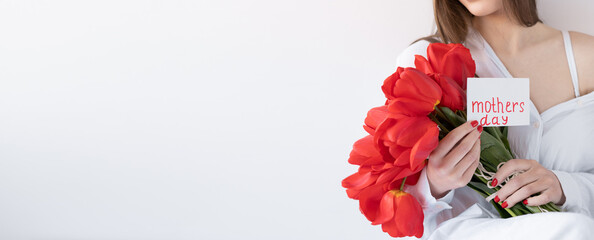 Flowers for Mother's Day. Girl with tulips and a postcard on a white background. Happy mother's day. Banner