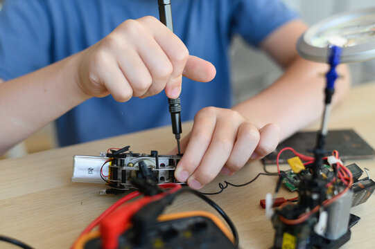 STEM Hobbies for advanced smart kids. Front view close up boy's hands carefully assembling drone toy with screwdriver