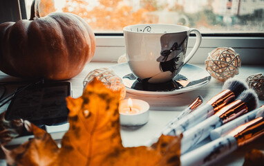 Cup of coffee with pumpkins on wooden white background with a makeup brushes in autumn. Flatlay
