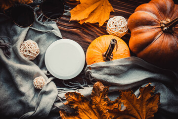 Cosmetics, pumpkins and sunglasses on wooden brown background and grey scarf. Flatlay	