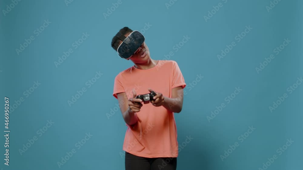 Poster young person playing video games with joystick and vr glasses in studio with blue background. woman 