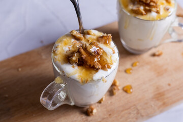 Cups of yogurt with honey and nuts on white background