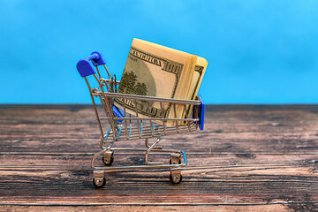 In the background is a cart with a bundle of dollars.