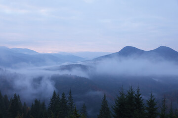 Obraz premium Beautiful view of mountains covered with fog during sunrise