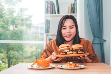 Asian woman enjoys fatty and cholesterol-rich fried chicken and hamburgers without worrying about...