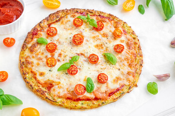 Zucchini crust pizza with tomato sauce, mozzarella cheese, fresh tomatoes and basil on a white wooden background. Zucchini pizza Margarita. Healthy dish.