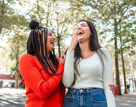 Laughing diverse friends standing on street