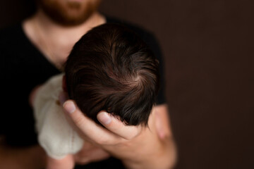 Obraz na płótnie Canvas the head of a newborn in the palm of the father. small head of newborn