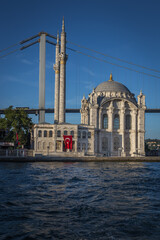 Fototapeta na wymiar Exterior of the famous Ortakoy Mosque or Grand Imperial Mosque located right next to the Bosphorus Bridge in Ortakoy, with a Turkish flag hanging from one of it's walls.