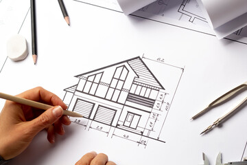 An architect draws a house project. Blueprints. Designer desktop. Engineering construction sketches.