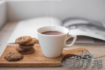 A cup of hot chocolate and cookies on wooden tray for winter background