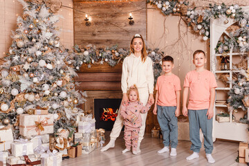 happy thirty-year-old woman and three cheerful children holding hands at Christmas