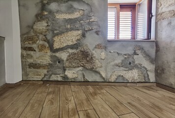 Mosaico de cor de madeira e roda-pé recentemente colocado num quarto com as paredes de pedra