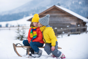 Kids kiss. Cute children boy and girl kissed on a winter walk in nature. Winter knitted kids clothes. Cold weather. Happy little kids wearing knitted hat, scarf and sweater.