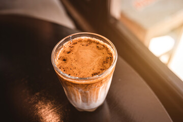 Hot coffee latte with latte art milk foam in glass mug with on wood desk on top view. As breakfast In a coffee shop at the cafe,during business work concept