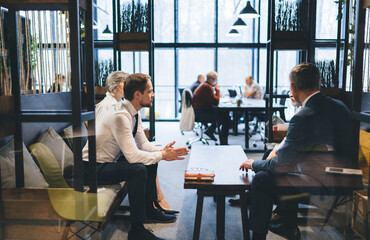 Businesspeople discussing strategy on couch in office lounge zone