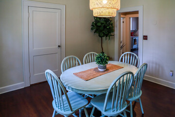 A small dining room with a statement rattan lighting ficture and a painted blue dining room table