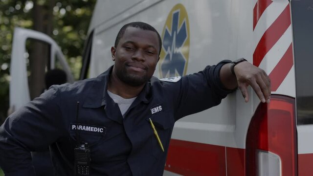 Positive african american paramedic posing near ambulance outdoors