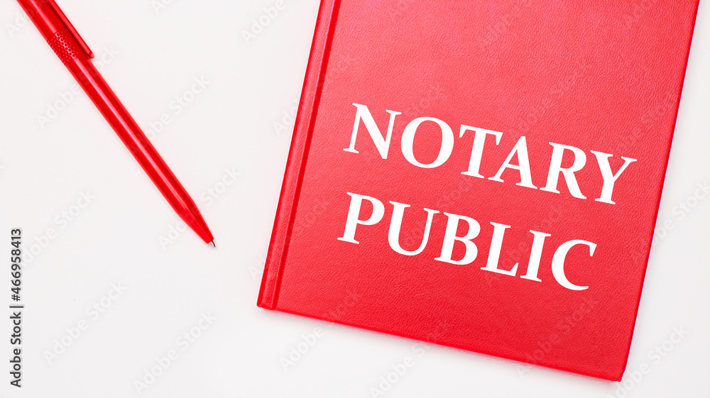 Poster the text notary public is written on a red notepad near a red pen on a white table in the office. bu