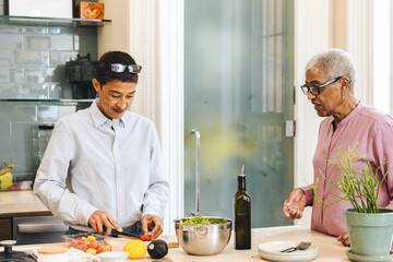 Mixed race woman prepares a salad at home while her mother watches