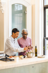 Two mature women standing together in the kitchen preparing dinner