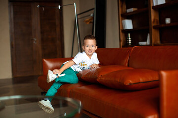 Five year old boy reclining on a leather couch