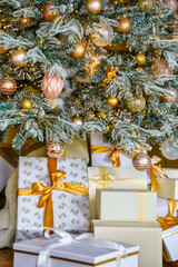 New Year's gifts under a Christmas tree decorated with golden toys. Close-up