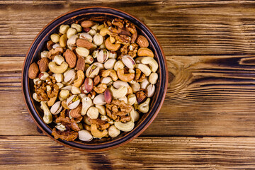 Various nuts (almond, cashew, hazelnut, pistachio, walnut) in ceramic plate on a wooden table. Vegetarian meal. Healthy eating concept. Top view